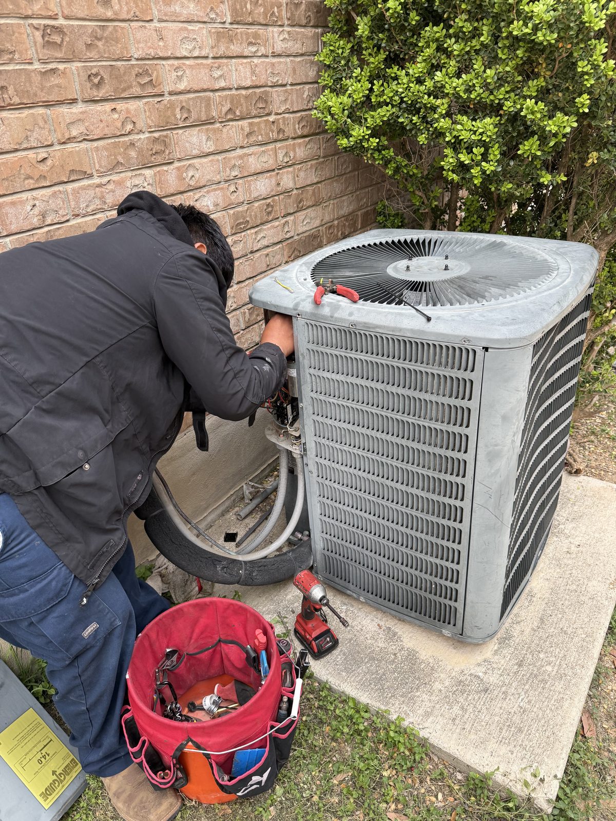 AC repair technician working on outdoor unit in San Antonio
