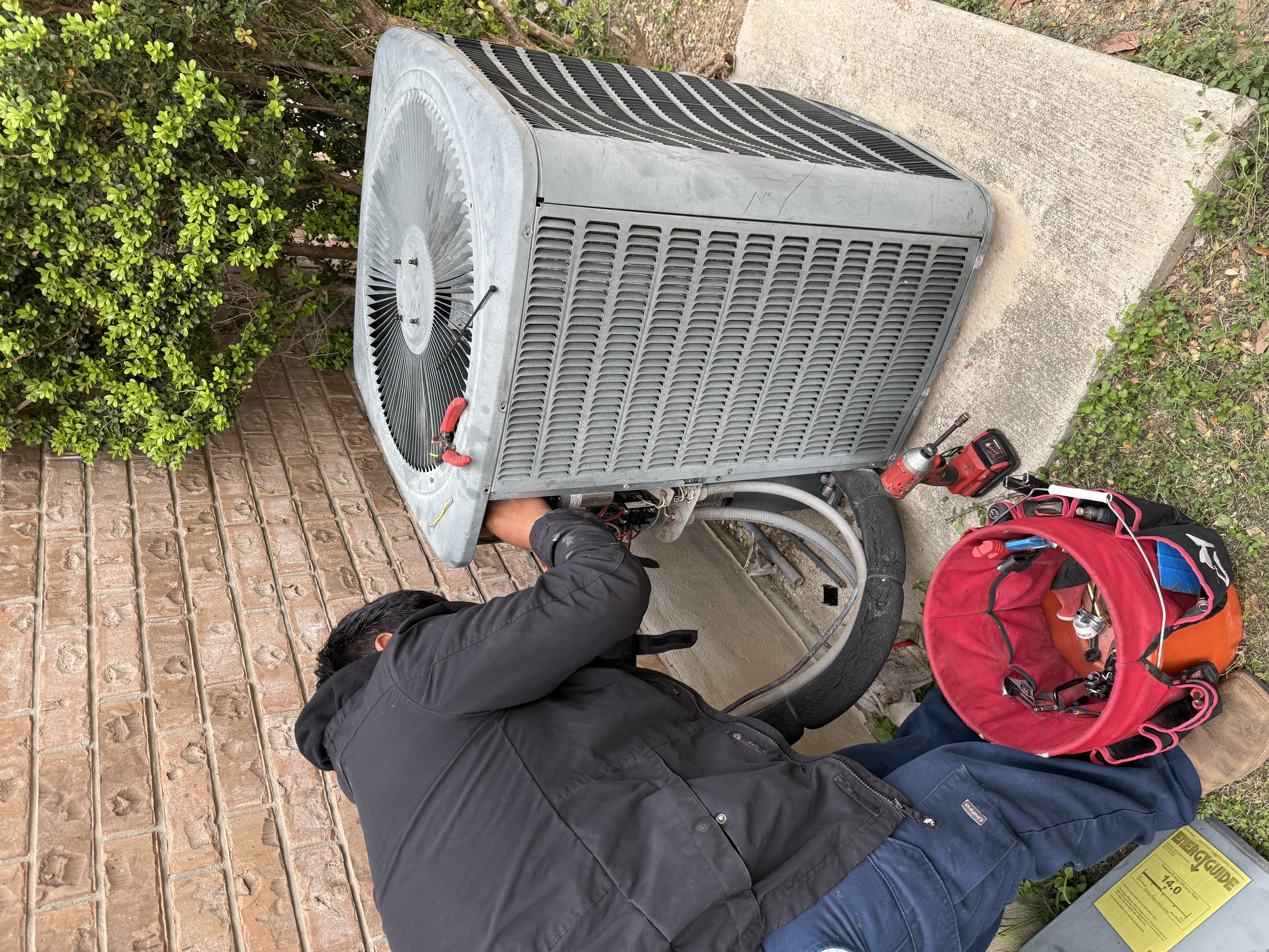 Emergency HVAC technician repairing outdoor unit in San Antonio